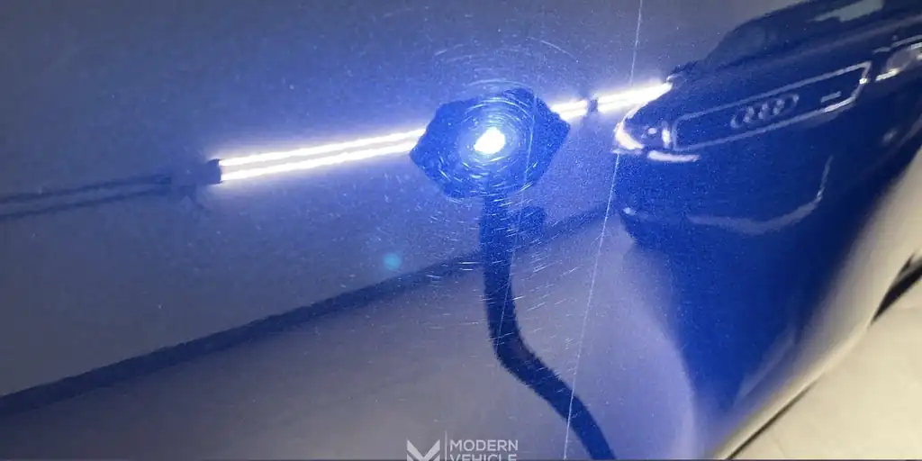 Black BMW paint under an inspection light, swirls visible