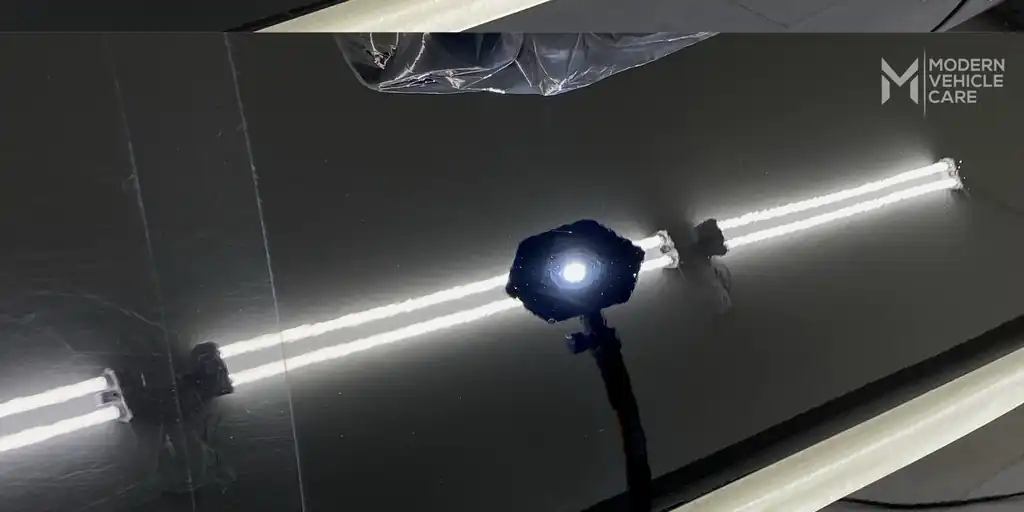 The same black paint after correction, strip lights reflected clean