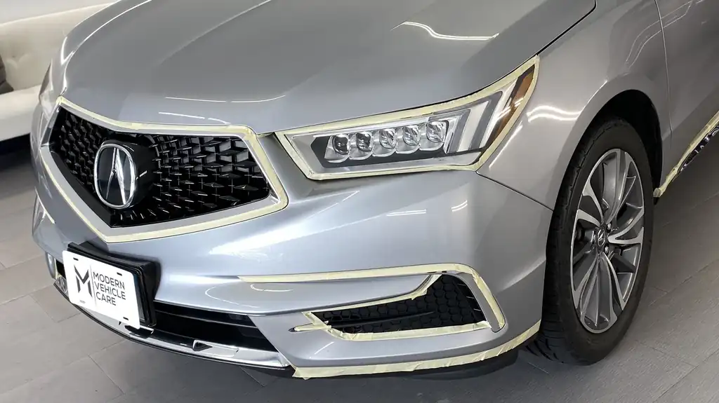 Silver Acura with the headlight and grille taped off with masking tape