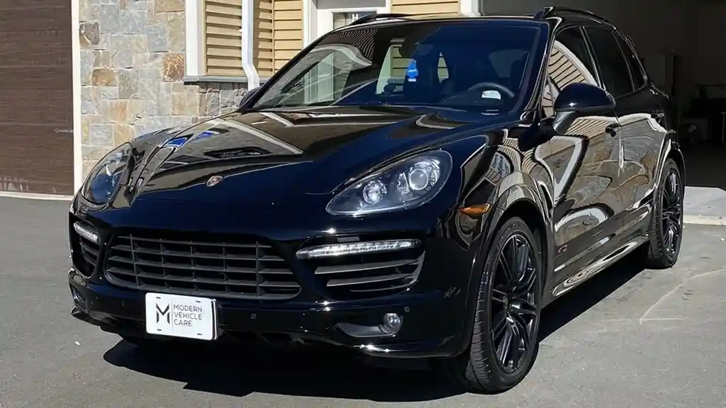 Black Porsche SUV head-on with a Modern Vehicle Care plate, hood and fenders glossy